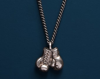 May include: A silver chain necklace with a pendant of two silver boxing gloves.