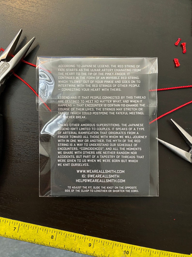 May include: Red string of fate bracelet with a white background and text explaining the legend of the red string of fate. The text includes the website and social media handles for Weareallsmith.