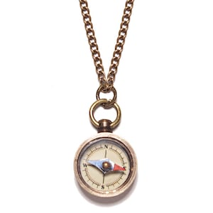 May include: A gold compass necklace with a chain. The compass face is white with black markings and a red and blue needle.