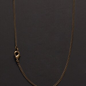 May include: A gold chain necklace with a lobster clasp closure.