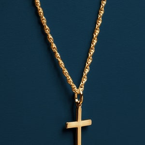May include: A gold chain necklace with a simple gold cross pendant.