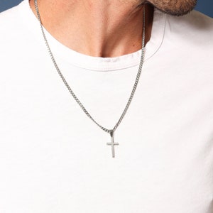 May include: A silver chain necklace with a small silver cross pendant.