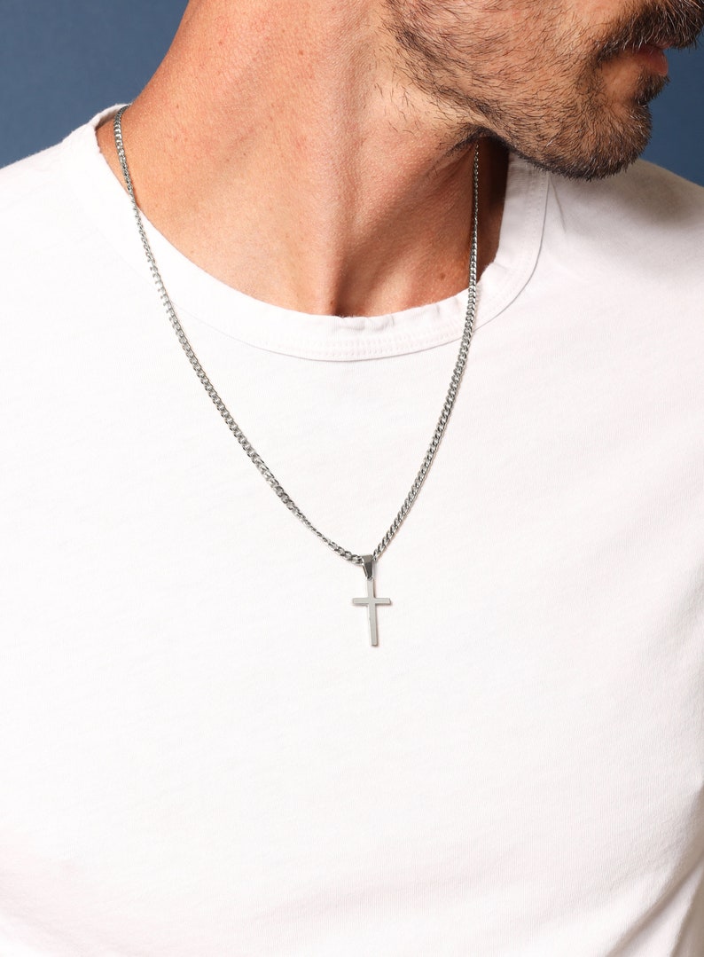 May include: A silver chain necklace with a small silver cross pendant.