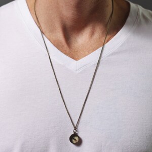 May include: A silver chain necklace with a small compass pendant.