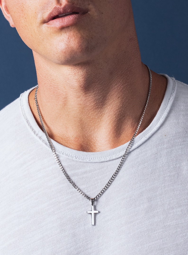 May include: A silver chain necklace with a small silver cross pendant.