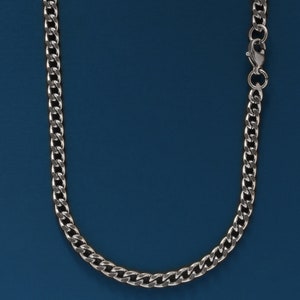 May include: A silver chain necklace with a lobster clasp closure. The chain is on a blue background.