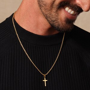 May include: A gold rope chain necklace with a small gold cross pendant.