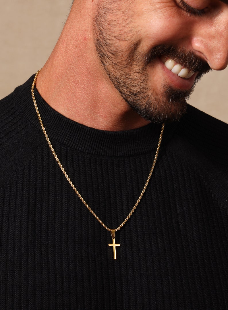 May include: A gold rope chain necklace with a small gold cross pendant.