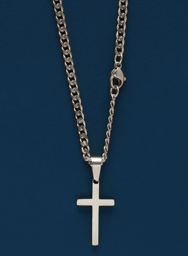 May include: A silver chain necklace with a silver cross pendant.