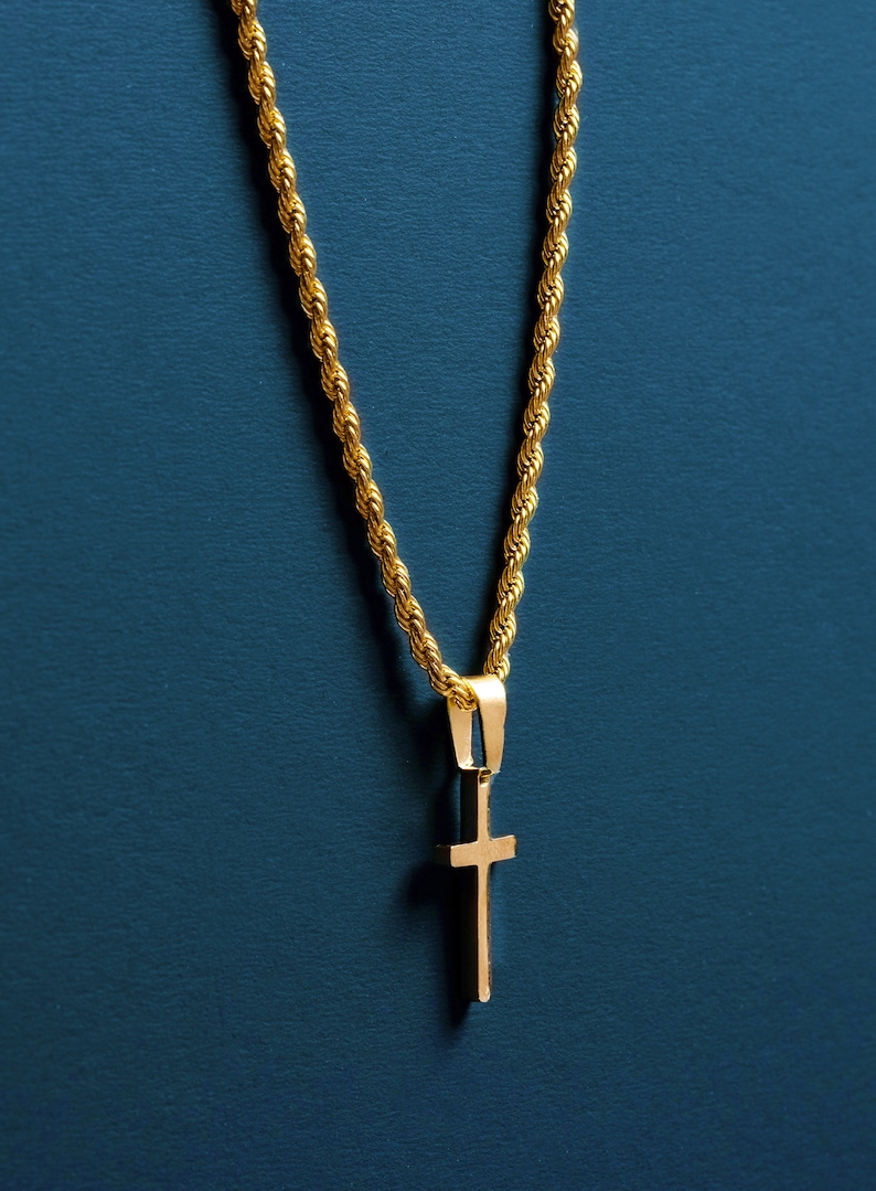 May include: A gold chain necklace with a small gold cross pendant. The necklace is on a blue background.