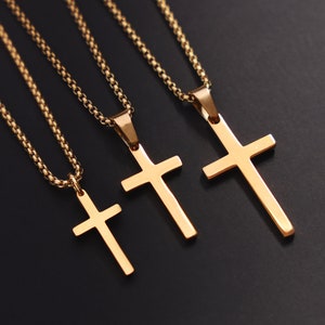 May include: Three gold chain necklaces with cross pendants of varying sizes. The chains are delicate and the crosses are simple and elegant.