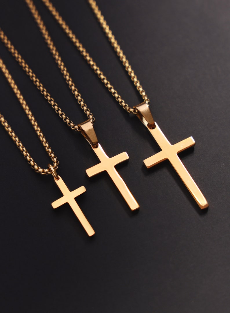 May include: Three gold chain necklaces with cross pendants of varying sizes. The chains are delicate and the crosses are simple and elegant.