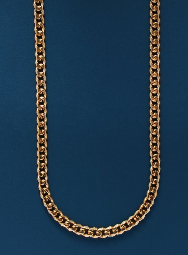 May include: A gold chain necklace on a blue background.