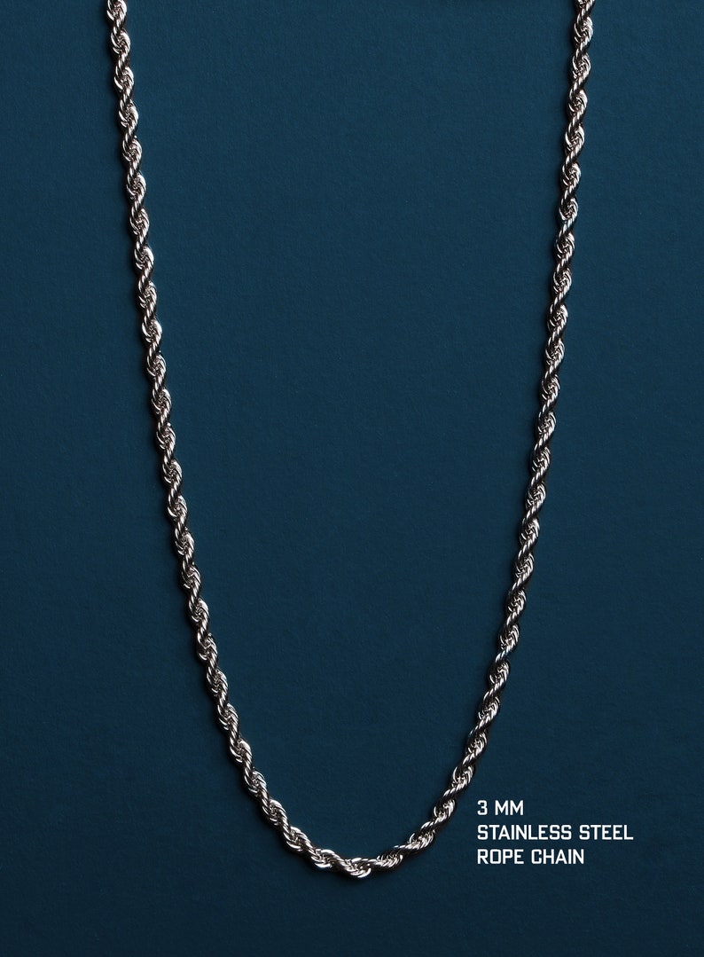 May include: A silver-colored stainless steel rope chain necklace, 3 mm thick, against a dark teal background. The chain is displayed vertically, showcasing its twisted rope design. The text "3 mm Stainless Steel Rope Chain" is visible.