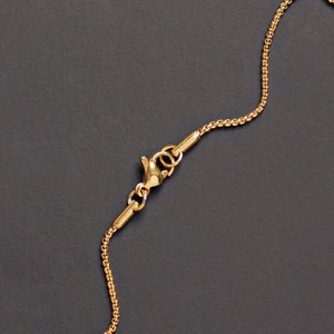 May include: A gold chain necklace with a lobster clasp closure. The chain is made of small, linked circles.