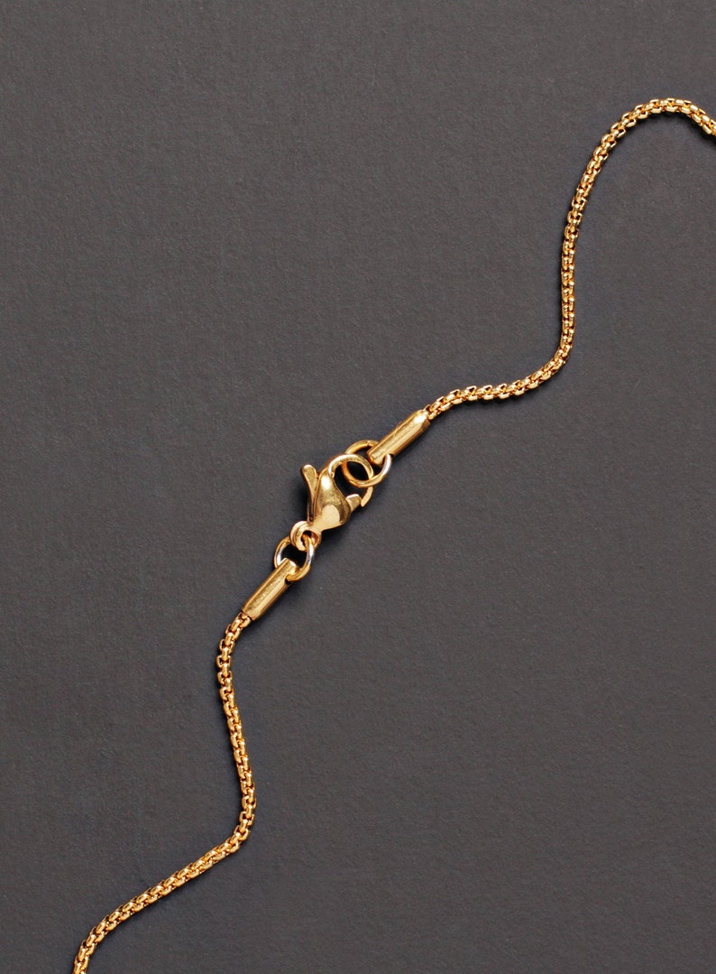 May include: A gold chain necklace with a lobster clasp closure. The chain is made of small, linked circles.