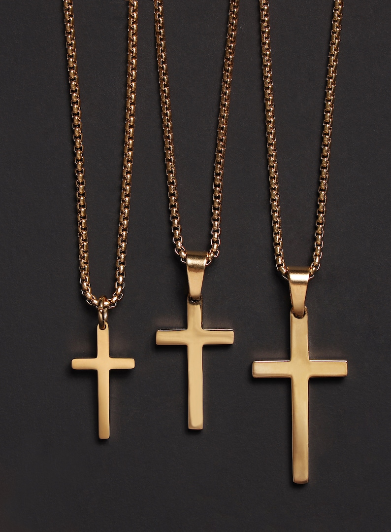 May include: Three gold chain necklaces with different sized cross pendants. The chains are all the same style, with a box chain design.