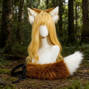 Può includere: Un set cosplay da volpe con una parrucca bionda, orecchie da volpe e una coda soffice. Le orecchie sono marroni e bianche, e la coda è marrone e bianca. Il set include un cinturino nero per la coda.