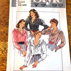 May include: A vintage sewing pattern showing illustrations of blouses with different styles. The blouses have features such as ruffles, bows, and patterned materials. The pattern includes sizes 0, 12, 14, and 16. The word "Style" is at the top.