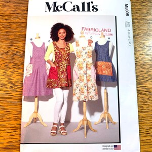 Peut inclure: Un patron de couture pour une robe avec trois styles différents. Le patron est de McCall's et est pour les tailles S-M-L-XL. La robe est présentée dans trois tissus différents : un imprimé floral, un imprimé rouge et or et un tissu denim.