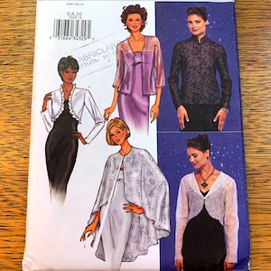 May include: A sewing pattern featuring four different designs for women's tops and jackets. The pattern includes a white lace bolero, a purple satin jacket, a black lace top, and a white lace cape. The pattern is printed on a white background with a blue and white starry sky pattern.