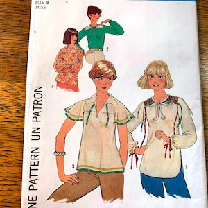 May include: A sewing pattern for a blouse with three different styles. The pattern includes instructions for a white blouse with a green trim, a white blouse with a red trim, and a green blouse with a white collar.