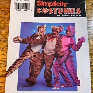 May include: Simplicity Costumes pattern showing three people in animal costumes: a tiger, a bear, and a dragon. The tiger costume is brown with black stripes, the bear costume is brown, and the dragon costume is pink and purple. The pattern is labelled "Simplicity Costumes".
