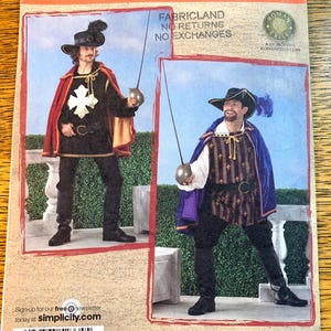 May include: A Simplicity sewing pattern showing two men in Renaissance costumes. One wears a black tunic with a white cross, red cape, and hat. The other wears a striped tunic, blue cape, and hat. The pattern includes the text "FABRICLAND NO RETURNS NO EXCHANGES".