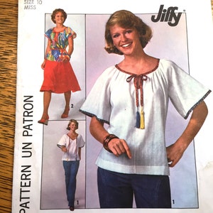 May include: Vintage sewing pattern for a white peasant blouse with a tie at the neckline and tassel accents. The pattern is from Jiffy and is for size 10.