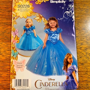 May include: A Simplicity home sewing pattern for a Cinderella dress. The pattern cover features images of a girl and a doll wearing the blue dress. The pattern size is Euro 3-8.