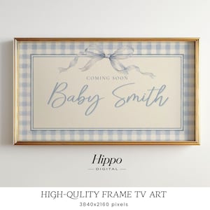 May include: A digital television art display in a gold frame featuring a light blue and white gingham border. The center cream panel displays a light blue watercolor bow above the text "COMING SOON" and the name "Baby Smith" in blue script.