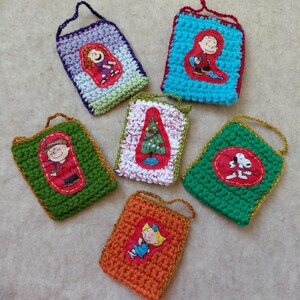 May include: A collection of six handmade crochet ornaments. Each ornament features a different character from a cartoon series, with a colorful design and a loop for hanging. The ornaments are in various colors, including green, orange, and blue.
