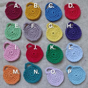 May include: A collection of sixteen small, round, crocheted items in various colors, each with a small loop handle. Colors include red, yellow, blue, green, purple, pink, orange, and teal. The items are arranged in four rows of four.