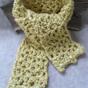 May include: A yellow crocheted scarf with a delicate openwork pattern and white pearl embellishments.