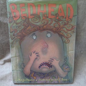 May include: A children's book titled "BEDHEAD" with an illustration of a wide-eyed, freckled character with wild red hair. The character is clutching their face in a distressed manner. The book cover is green with orange lettering.