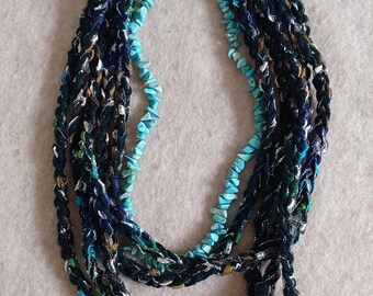 May include: A multi-strand necklace with black, blue, and green braided fabric and turquoise-colored beads.