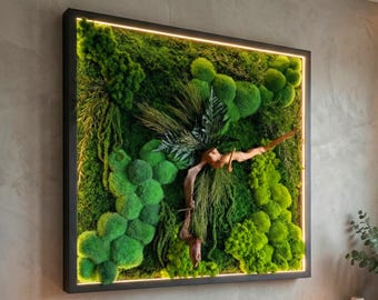 May include: Square framed wall art featuring a vibrant arrangement of green moss and plants. The artwork includes a wooden branch and fern accents, with a warm, glowing light around the inner frame. The frame is black.