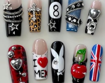 Op de afbeelding: Tien kunstnagels met diverse ontwerpen. De nagels tonen kleuren als zwart, rood, blauw en wit, met versieringen zoals sterren, harten en een kruis. Sommige nagels hebben een French tip-ontwerp, terwijl andere patronen en afbeeldingen tonen.