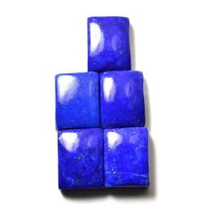 Può includere: Cinque pietre preziose di lapislazzuli rettangolari disposte in gruppo. Ogni pietra presenta un colore blu reale profondo e vibrante con sottili variazioni naturali e piccole macchie di pirite dorata visibili sulle superfici levigate.