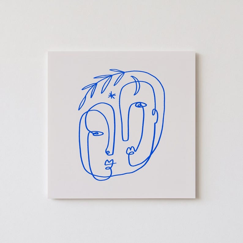 May include: A minimalist art print featuring a blue line drawing of two faces. The artwork is on a white background and includes a star and leaf-like details. The faces are stylized with simple lines, creating a modern and abstract aesthetic.