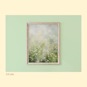 May include: A vertical rectangular wall art piece featuring an impressionistic oil painting of a field of small white wildflowers with soft green and yellow foliage, enclosed in a light-toned wooden frame with a visible grain texture.