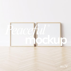 Può includere: Due cornici quadrate in legno con interni bianchi sono appoggiate a una parete bianca. Le cornici hanno una finitura in legno chiaro e sono posizionate su un pavimento in legno chiaro. Il testo "Peaceful mockup" è sovrapposto alle cornici.