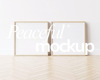 May include: Two square wooden picture frames with white interiors lean against a white wall. The frames have a light wood finish and are positioned on a light-colored wooden floor. The text "Peaceful mockup" is overlaid on the frames.