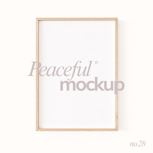 May include: A rectangular wooden picture frame with a white interior. The text "Peaceful mockup" is printed in a light gray color across the center of the frame. The number "no.28" is printed in the bottom right corner.