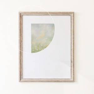 May include: A rectangular picture frame with a weathered light brown wood finish and a white mat board. A circular overlay highlights a portion of an abstract painting featuring soft, blended shades of pale green, yellow, and white tones.