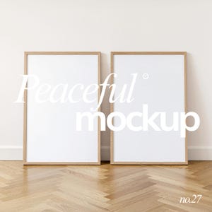 Puede incluir: Dos impresiones artísticas blancas enmarcadas con marcos de madera clara se apoyan contra una pared blanca. El texto "Peaceful mockup" se muestra en las impresiones. El suelo es de madera marrón claro. El número "no.27" está en la esquina inferior derecha.