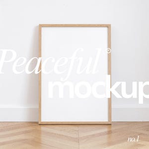 May include: A rectangular wooden picture frame with a white interior, leaning against a white wall. The frame is on a wooden floor. The words "Peaceful mockup" are written in white across the frame. The number "no.1" is in the bottom right corner.