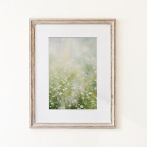 May include: A framed wall art piece featuring an impressionistic painting of a field of small white flowers with green stems and foliage. The artwork is encased in a light-toned, weathered wood frame with a wide white mat border surrounding the print.