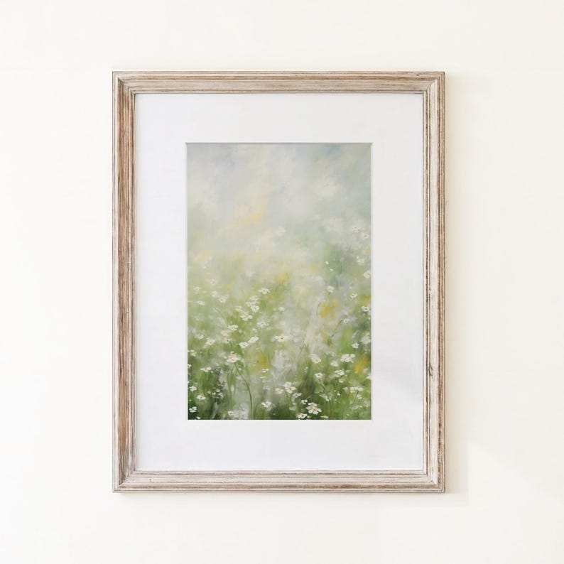 May include: A framed wall art piece featuring an impressionistic painting of a field of small white flowers with green stems and foliage. The artwork is encased in a light-toned, weathered wood frame with a wide white mat border surrounding the print.