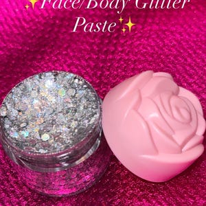 May include: A jar of silver glitter paste next to a pink rose-shaped container. The text on the image reads "Face/Body Glitter Paste". The container is for face and body glitter paste, with a size of 20g.